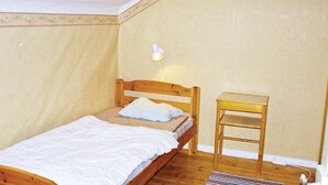 Una camera piccola con un letto singolo, una testiera in legno, un comodino e una lampada fissata al muro.