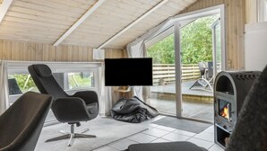 Ett modernt utomhusområde där man kan umgås, med en öppen spis, bekväma sittplatser, en platt-TV och utsikt över omgivningen.