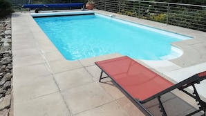 A rectangular swimming pool with a tiled deck, a red lounge chair, and a blue pool cover. - Lovely home in Cadouarn with WiFi (Cadouarn)