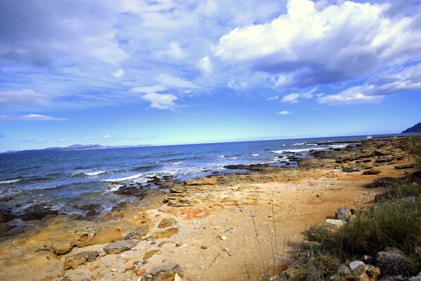 A rocky coastal landscape with a clear sky and calm sea.