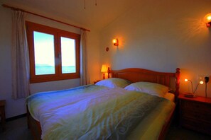 A bedroom with a bed, two bedside lamps, a nightstand, a window with curtains, and a wall-mounted light. - 44263 Romantic Sa Nau - 44263 Romantic vacation home Sa Nau (Colonia de Sant Pere)