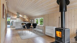 Een moderne keuken met houten lambrisering, een eethoek met stoelen, een fornuis en uitzicht op de omgeving.