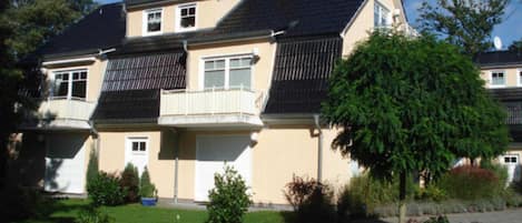 A two-story residential building with a balcony, satellite dish, and a well-maintained lawn.