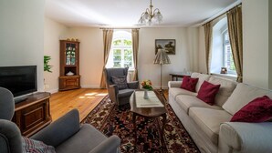 Una sala de estar con televisor, sofá, sillón y alfombra estampada.