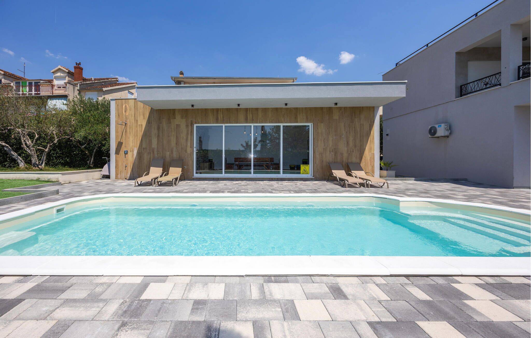 Ein moderner Poolbereich mit Pool, zwei Liegestühlen und einer Holzterrasse.