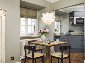 Une cuisine moderne avec un coin repas, comprenant une table en bois, deux chaises, un luminaire suspendu et un vase avec des fleurs.