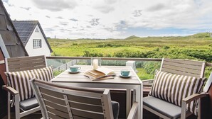Un balcon avec une table, des chaises et une vue sur un paysage verdoyant.
