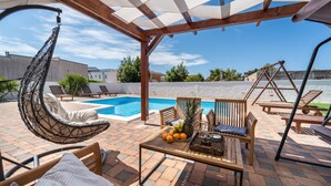 A covered outdoor area with a pool, seating, and a swing set. - Gorgeous home in Biograd (Biograd)