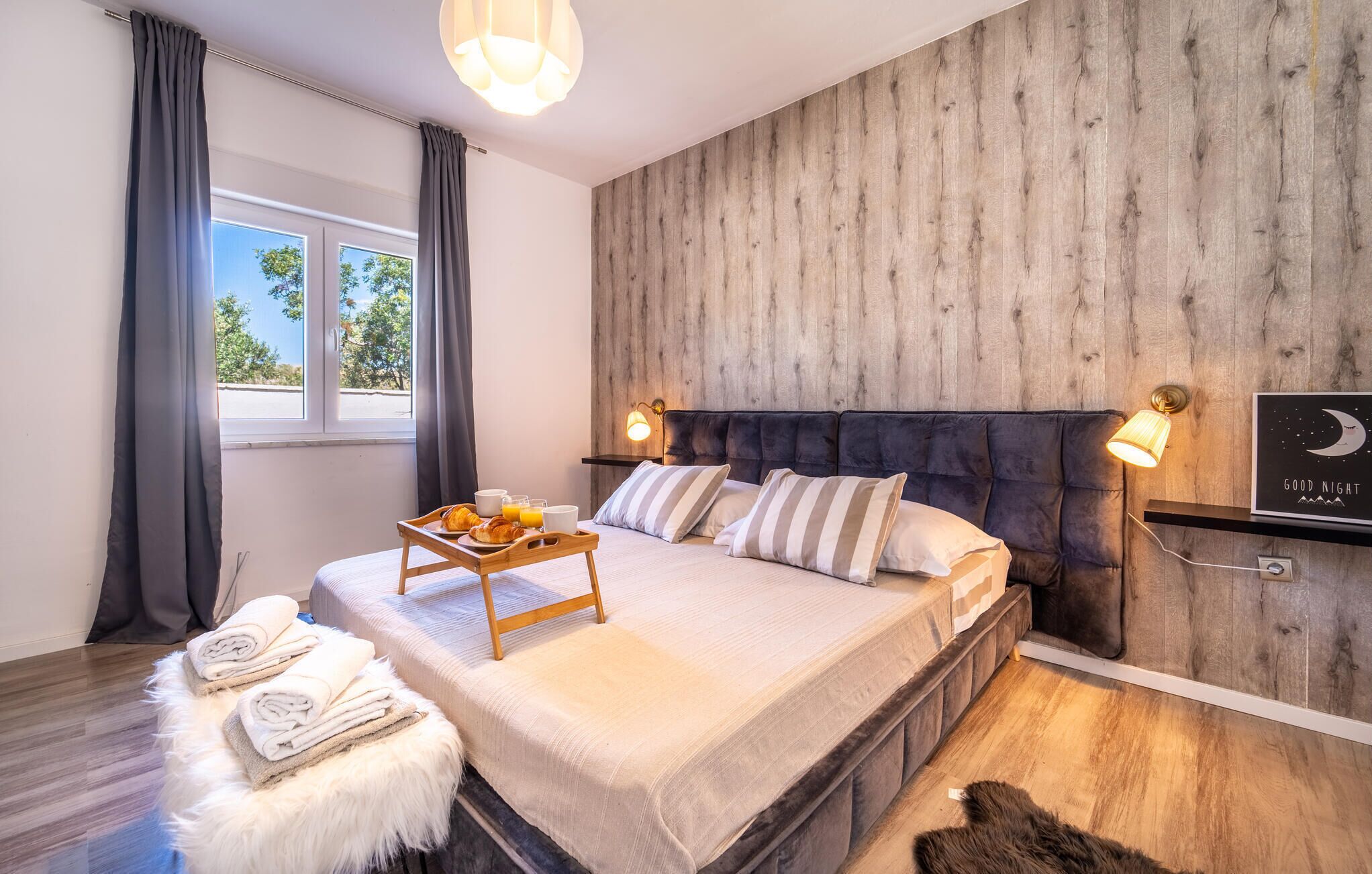 Ein Schlafzimmer mit Holzwand, einem Bett mit Frühstücksbrett und einem Poster vom Nachthimmel.