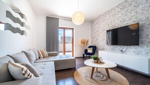 A modern living room with a sofa, a round coffee table, and a flat-screen TV mounted on a brick wall. - Gorgeous home in Biograd (Biograd)