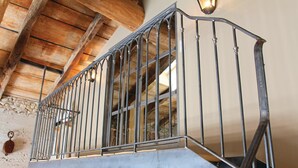 A metal staircase with a railing, wooden beams, and a stone wall. - Nice home in La Batie Rolland (La Batie Rolland)