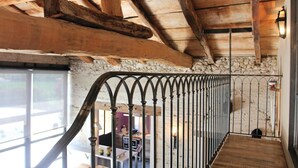 A wooden staircase with a metal railing leading to a room with stone walls and a window. - Nice home in La Batie Rolland (La Batie Rolland)