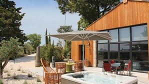 A modern outdoor patio with a hot tub, wicker chairs, and a table with umbrellas. - Nice home in La Batie Rolland (La Batie Rolland)