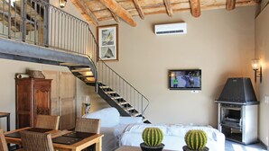 A spacious living room with a wooden staircase, a fireplace, a television, and two potted cacti. - Nice home in La Batie Rolland (La Batie Rolland)