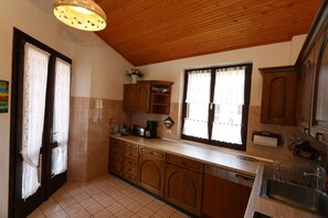 A kitchen with wooden cabinets, a dishwasher, and a window with curtains.