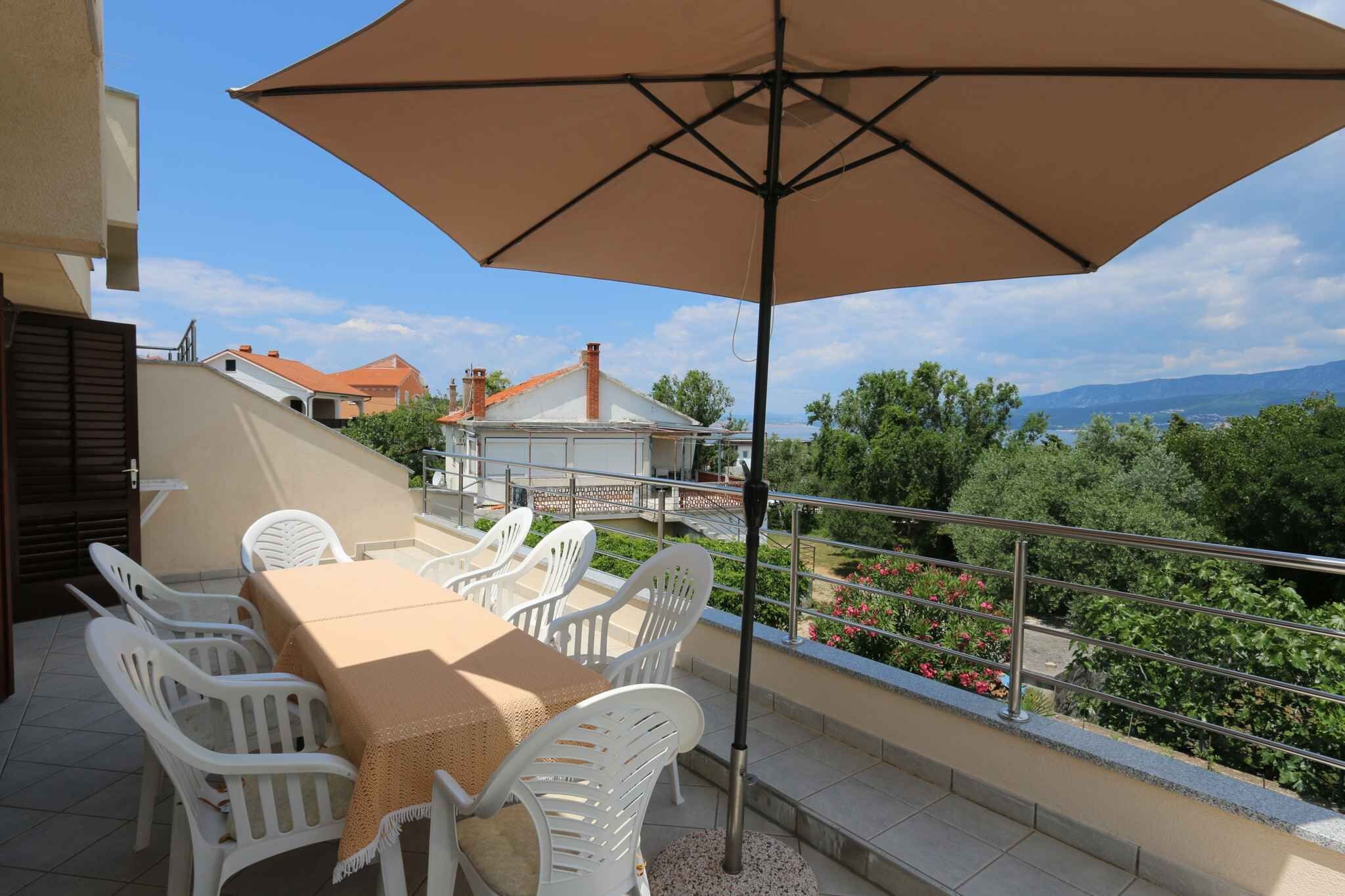 Une terrasse extérieure avec une table et des chaises, un grand parasol et une vue sur le paysage environnant.