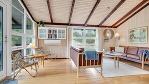 Una habitación acogedora con techo de madera, una estantería, un sofá, una mesa y una silla.