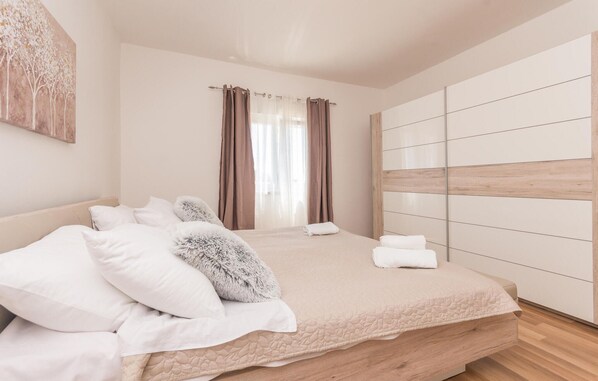Une chambre à coucher moderne avec un lit, des oreillers blancs, un plaid moelleux et une tête de lit en bois.