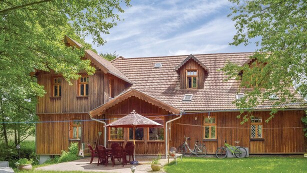 A wooden house with a tiled roof, a porch with chairs, and bicycles parked outside. - 2 bedroom cozy home in Dautphetal (Dautphetal)