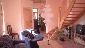 A cozy living room with a blue sofa, a wooden coffee table, a staircase, and a television on a wooden stand. - 2 bedroom cozy home in Dautphetal (Dautphetal)
