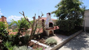 A garden with a small structure, possibly a barbecue area, surrounded by various plants and a tree. - Studio with balcony and air conditioning (Šilo)