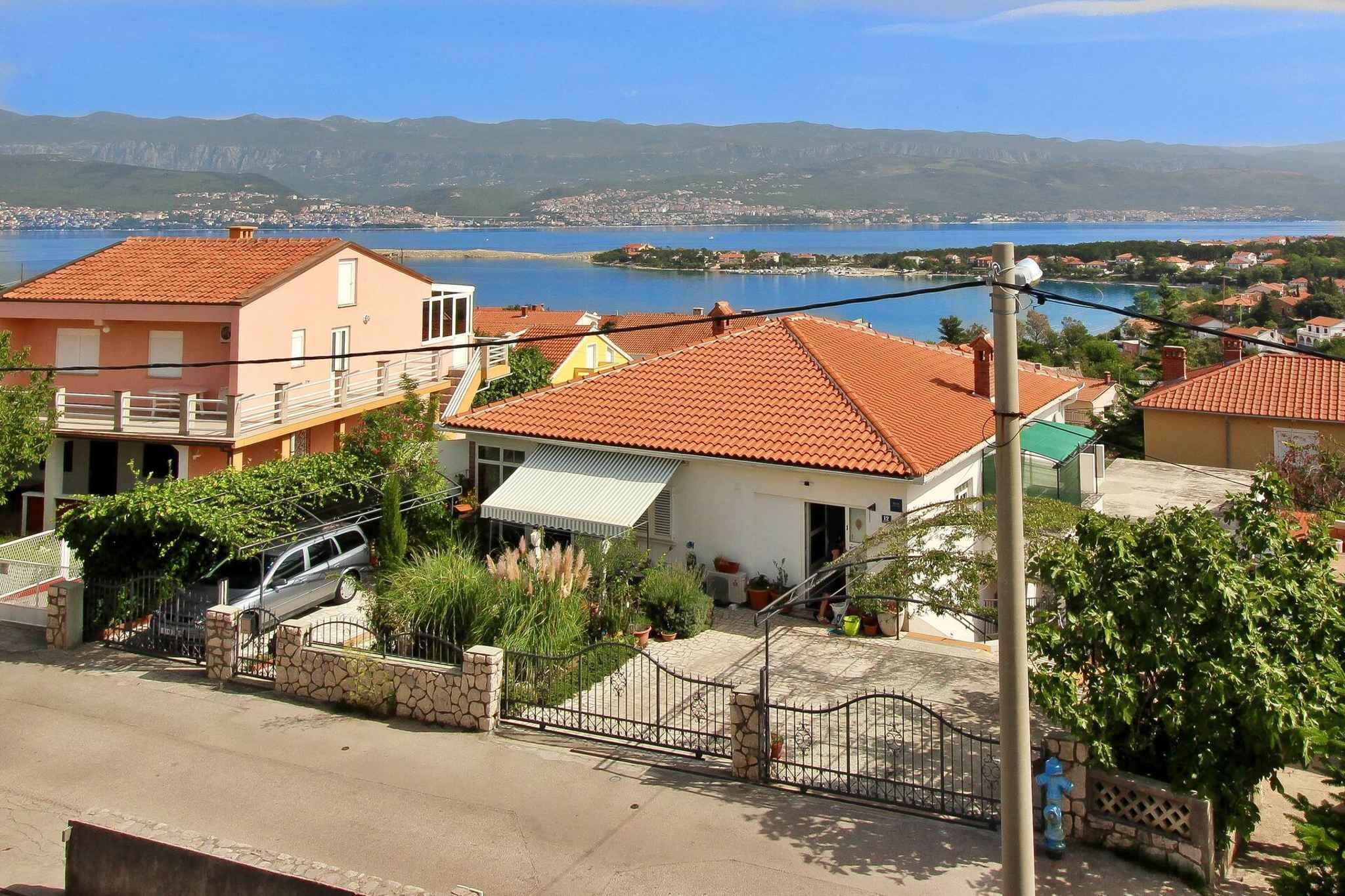 A coastal residential area with houses featuring red-tiled roofs and a view of the sea.
