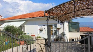 A house with a red-tiled roof, a stone wall, and a metal gate. - Studio with balcony and air conditioning (Šilo)