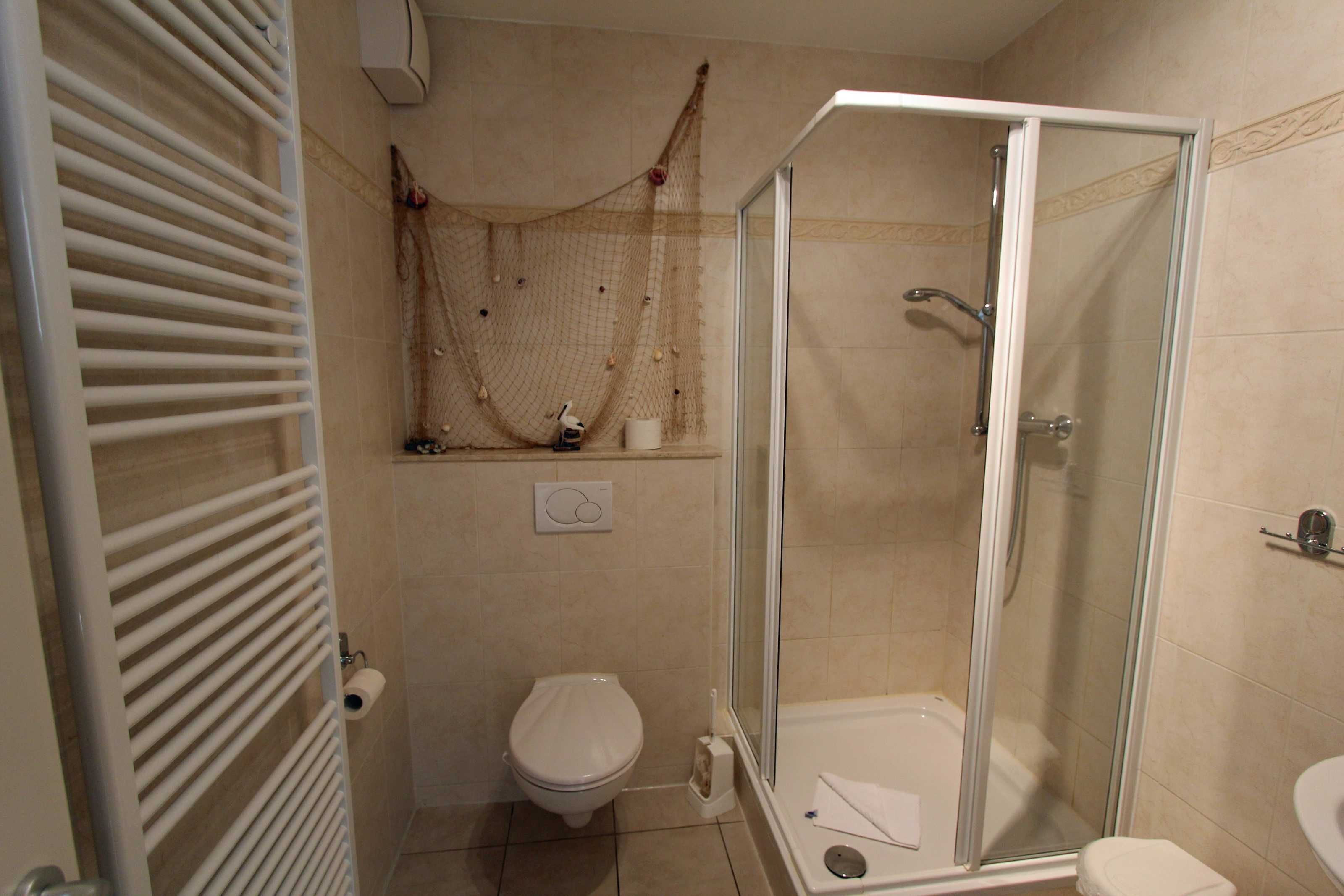 Une salle de bain avec une douche à parois de verre, des toilettes et un porte-serviettes.
