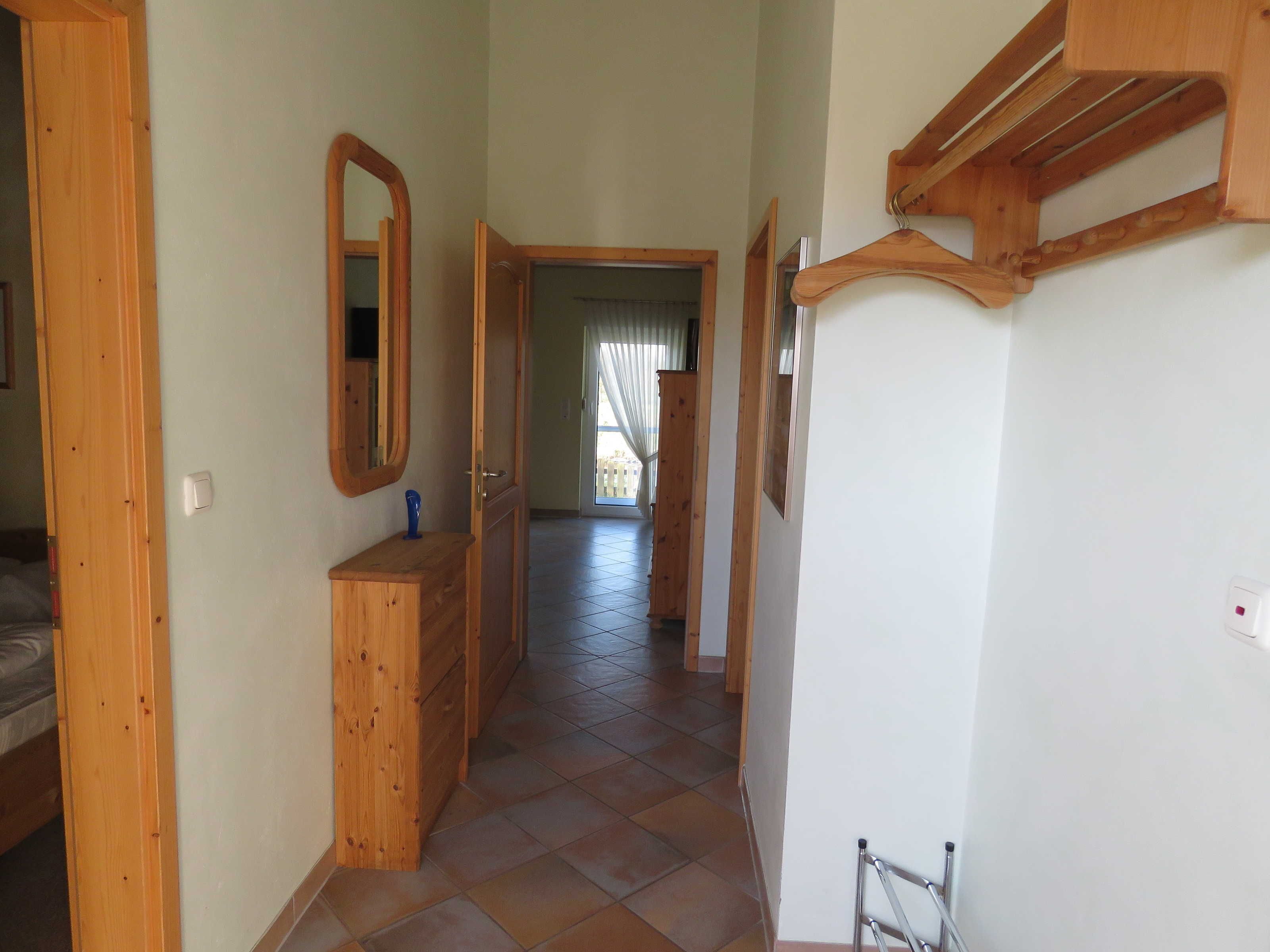 Un couloir avec des portes en bois, un miroir et un banc en bois.