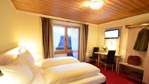 Habitació d'hotel amb un llit, un escriptori, una cadira i una televisió.