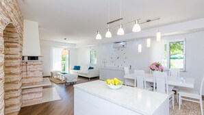 Una cocina moderna con una isla central, armarios blancos y una pared decorativa de piedra.