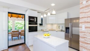 Una cocina moderna con armarios blancos, una isla central y un refrigerador empotrado.