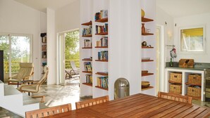 A spacious living area with a wooden dining table, comfortable seating, a bookshelf, and a view of the outdoors. - Cozy home in San Giuliano with WiFi (San Giuliano)