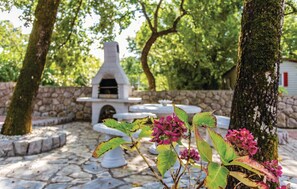 An outdoor patio with a stone floor, a white outdoor oven, and a stone wall. - 2 bedroom awesome apartment in Malinska (Malinska)