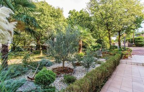 A landscaped garden with various plants, a paved walkway, and a stone wall. - 2 bedroom awesome apartment in Malinska (Malinska)