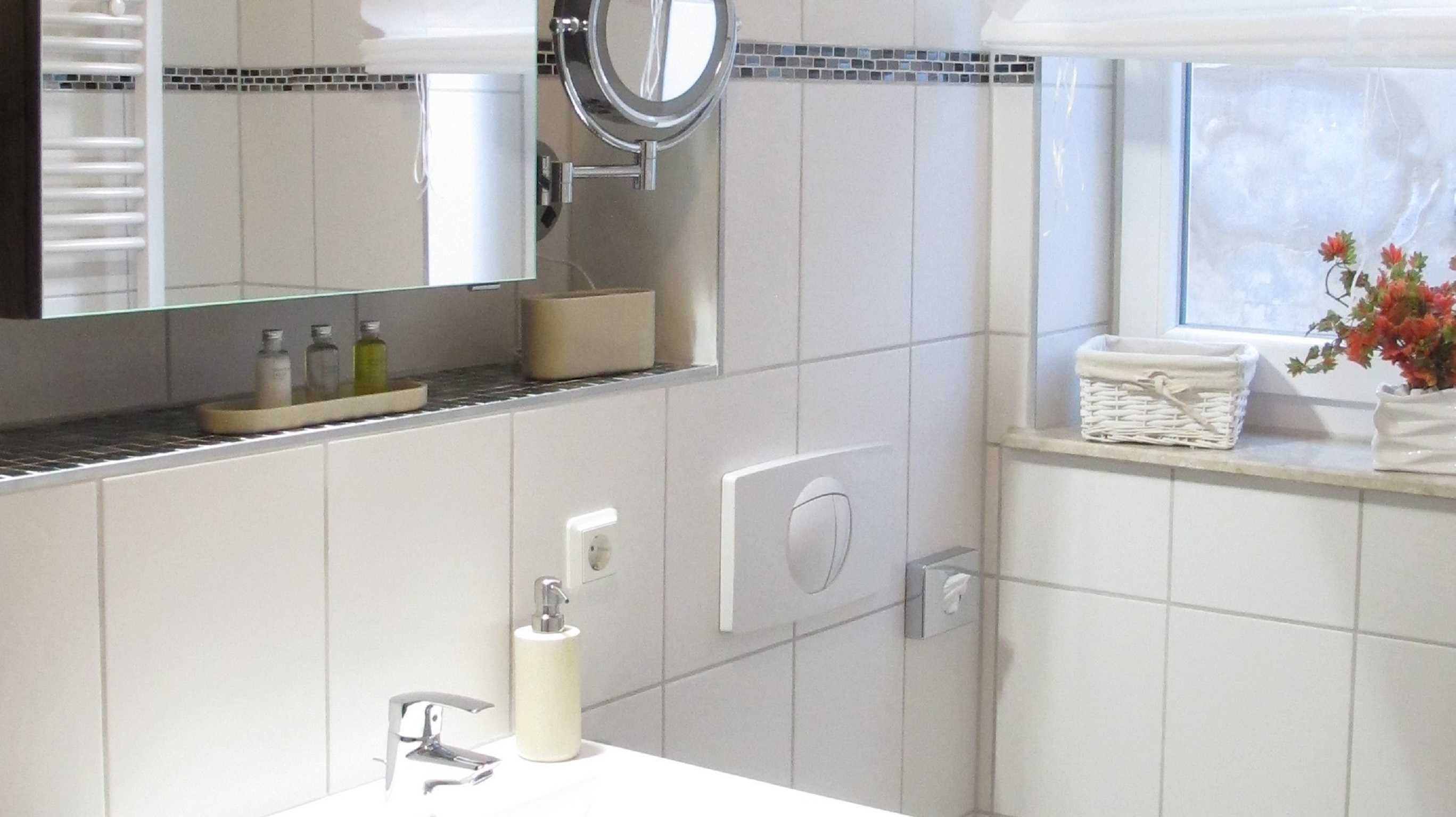 A modern bathroom with a white sink, a mirror, and a window with a view.