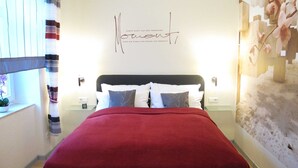 Une chambre à coucher comprenant un lit, des oreillers, une table de chevet, une horloge murale et un élément décoratif mural.