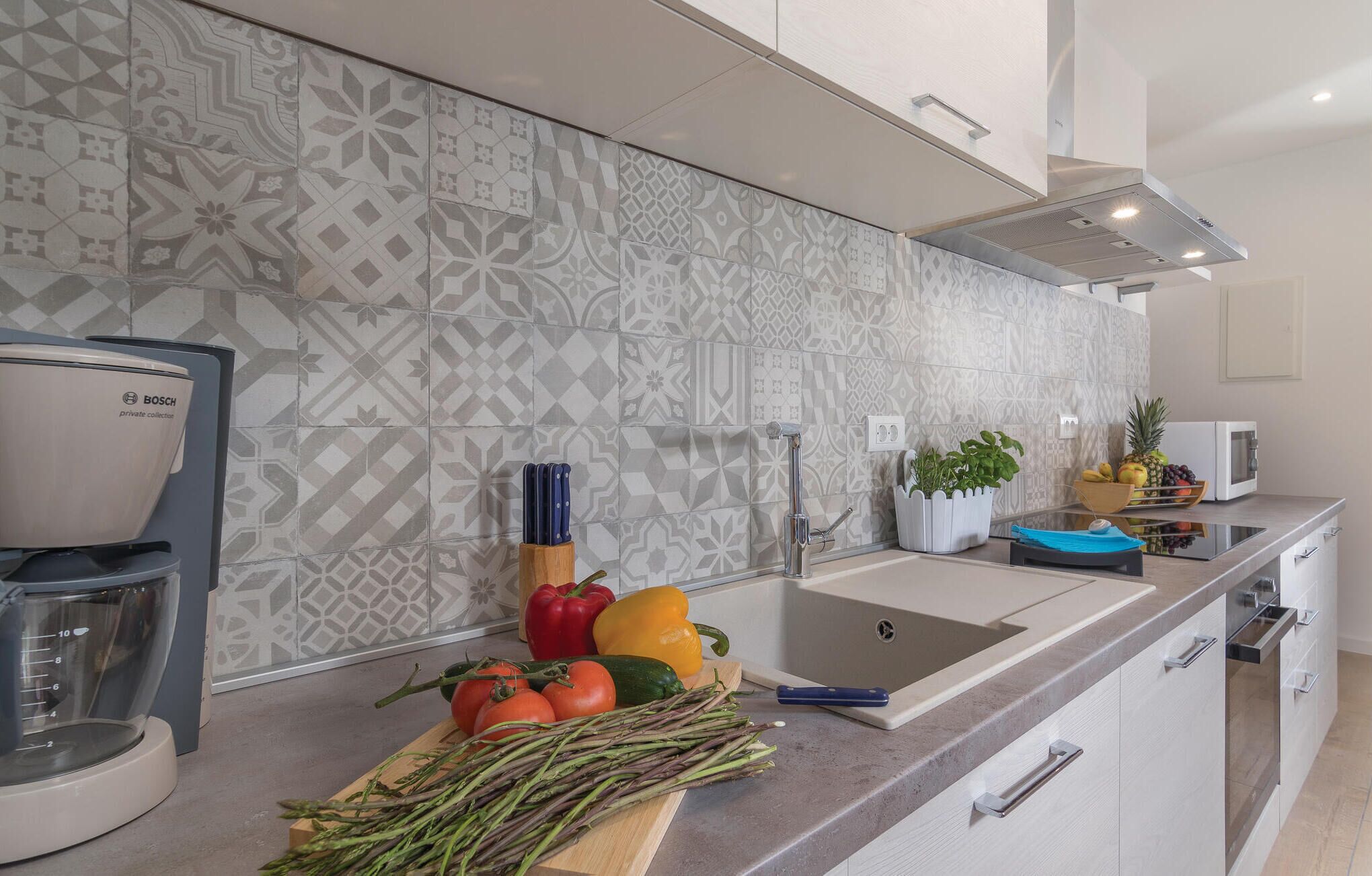 A modern kitchen with patterned backsplash, Bosch coffee maker, and fresh vegetables on the counter. - Lovely apartment in Labin with sauna (Labin)