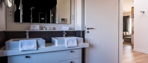 Une salle de bain moderne avec deux lavabos, un miroir et un porte-serviettes.