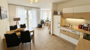 Una cucina moderna con mobili bianchi, un forno a microonde e una macchina da caffè. C'è un'area pranzo con tavolo e sedie.