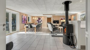 Et moderne køkken med en central ø, indbygget komfur og et spiseområde med et stort bord og stole.