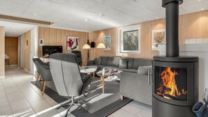 En moderne stue med pejs, sofa, spiseplads og fjernsyn.