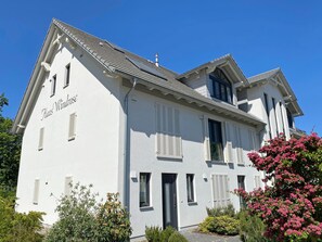 Un bâtiment à deux étages, doté d’une façade blanche, de volets et surplombant un ciel dégagé.