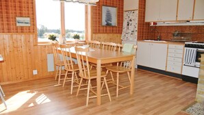 A wooden-paneled room with a dining table and chairs, a kitchen area with cabinets and appliances, and a window with a view of trees. - 2 bedroom beautiful home in åsensbruk (Åsensbruk)