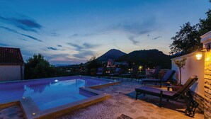 Un área de piscina en la azotea con sillones de descanso y un patio de piedra.