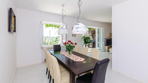 Un comedor con una mesa de madera oscura, sillas de mimbre y un florero con rosas rojas.