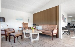 Ein modernes Wohnzimmer mit einer Couch, Sesseln, einem Couchtisch und einer Wand mit Holzverkleidung.