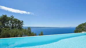 Un cielo azul despejado, una piscina y vista al mar.