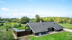 A modern house with a sloped roof, a covered patio, and a large yard. - Cozy home in Oksbøl with sauna (Oksbøl)