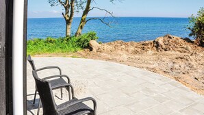 A patio with a view of the sea, a chair, and a pile of dirt.